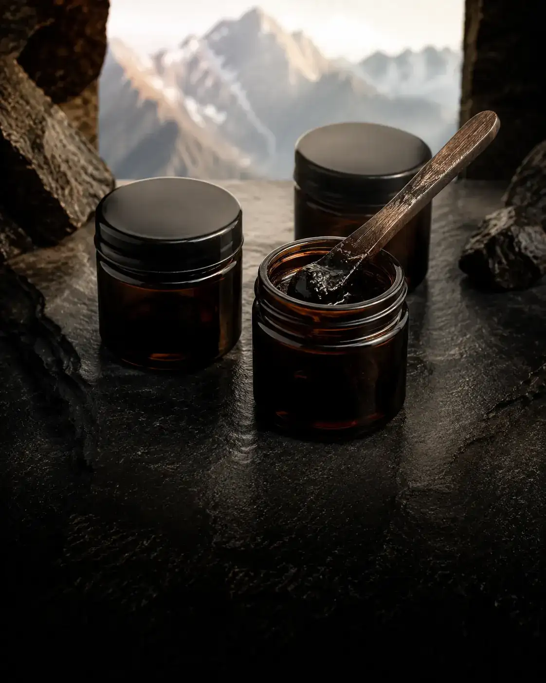 Unbranded amber jars of dark resin arranged on layered stone.