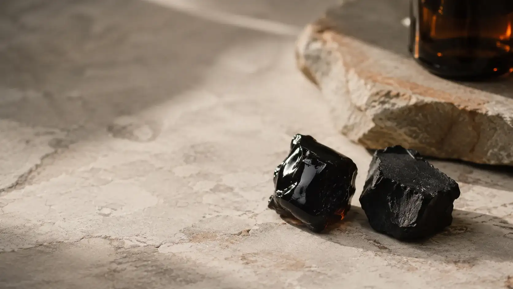 Two dark resin samples side by side on pale stone under the same daylight, one glossy and one dull and matt.