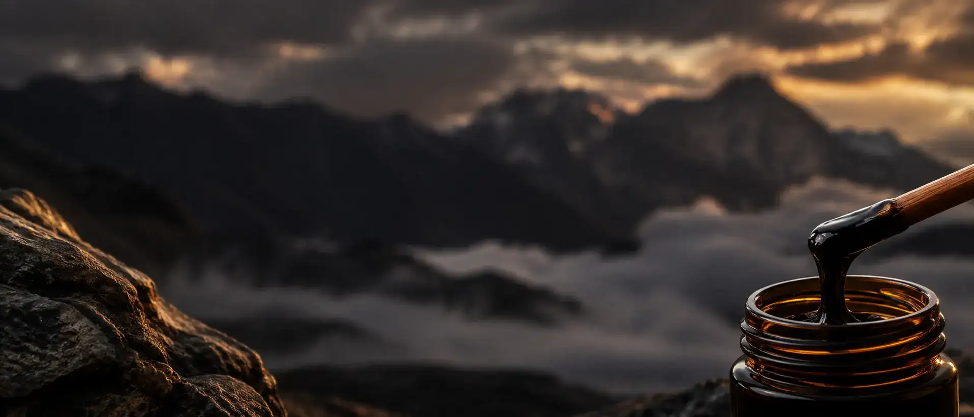 A small amber jar of dark resin on mountain stone at dusk.