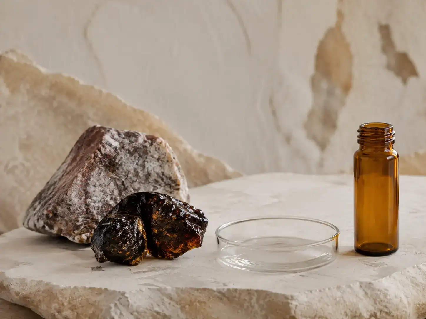 A measured dark resin sample beside an unbranded amber jar on pale stone.